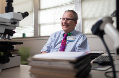 Dr. Brodell smiles while sitting behind desk